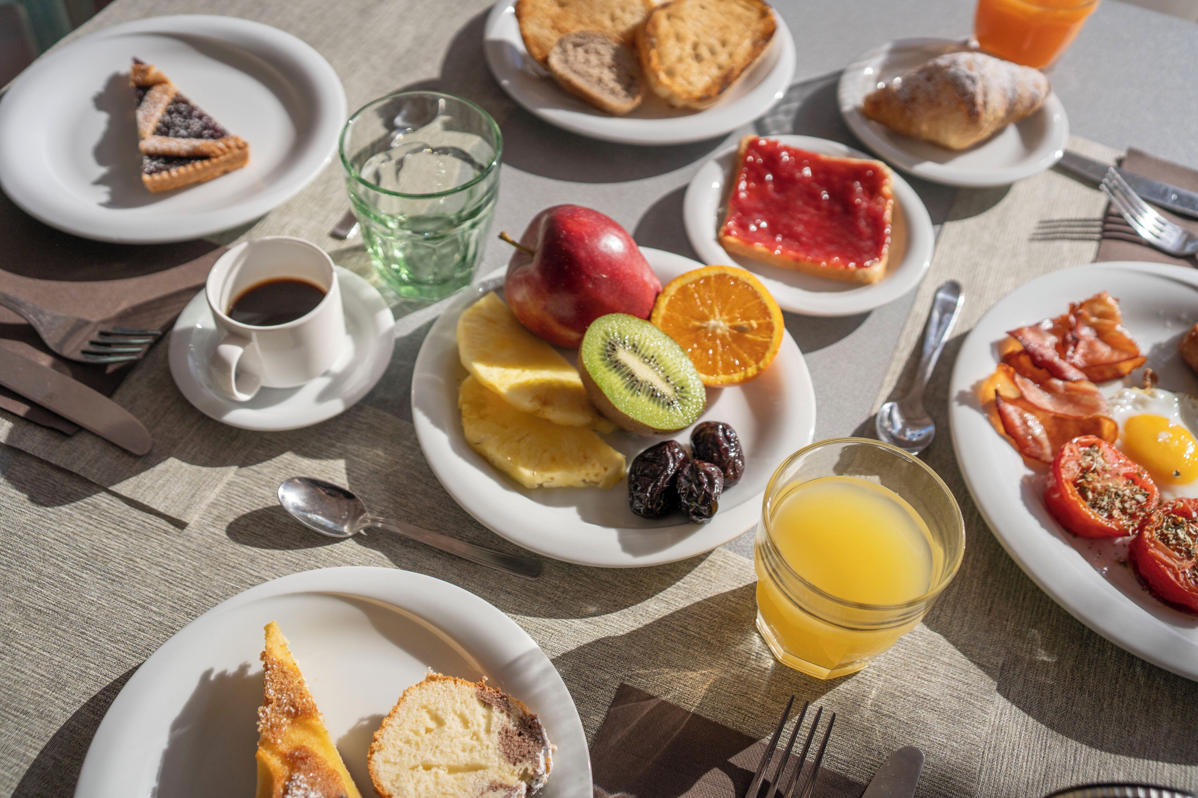 Desayuno servido con platos de comida, un vaso de jugo y una taza de café.