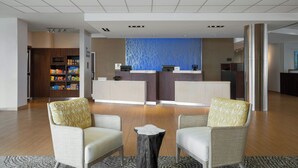 A hotel lobby with two armchairs, a reception desk, and a wall with a blue pattern.