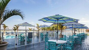 A deck with outdoor seating and umbrellas, overlooking a pool.