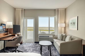 Une chambre d’hôtel équipée d’un bureau, d’une chaise, d’un canapé et offrant une vue sur l’extérieur grâce à de grandes fenêtres.