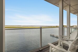 Un balcon avec vue sur une rivière et des bâtiments éloignés.