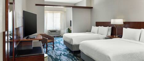 A hotel room with two beds, a desk with a flat-screen TV, a chair, and a large window with curtains.