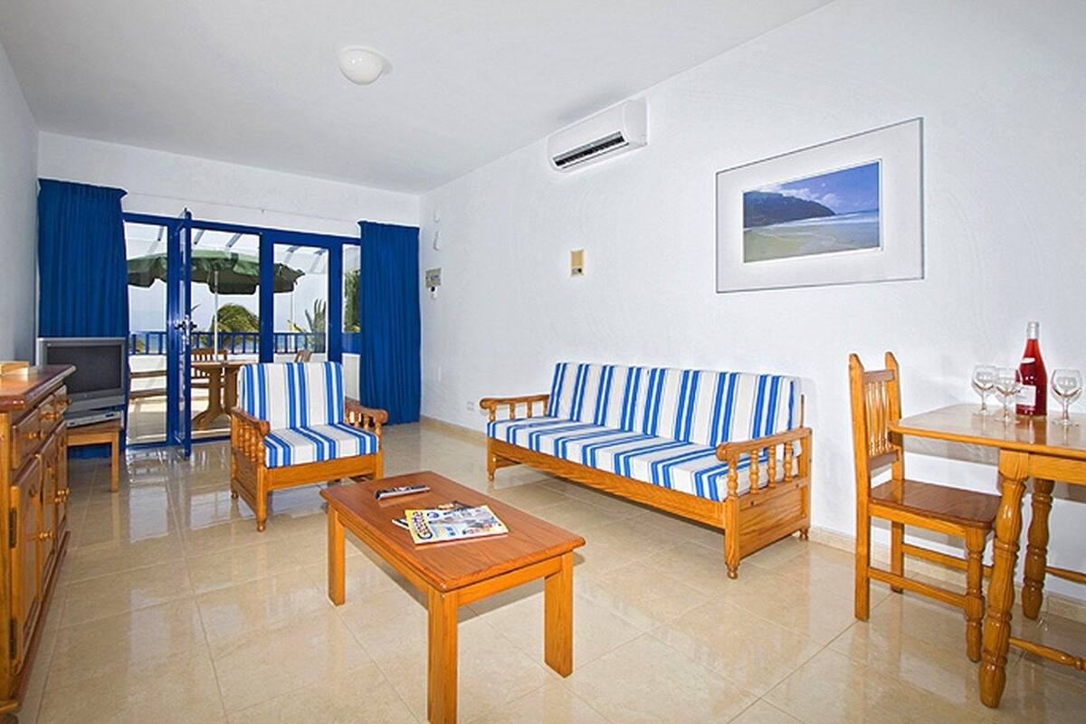 A living room with a sofa set, wooden coffee table, and a dining table with chairs.