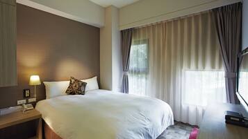 Une chambre d’hôtel avec un grand lit, une table de chevet avec une lampe, un téléphone et un bureau avec un ordinateur.
