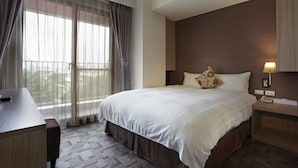 Habitación de hotel con una cama grande, un escritorio, una silla, una mesita de noche y una lámpara.