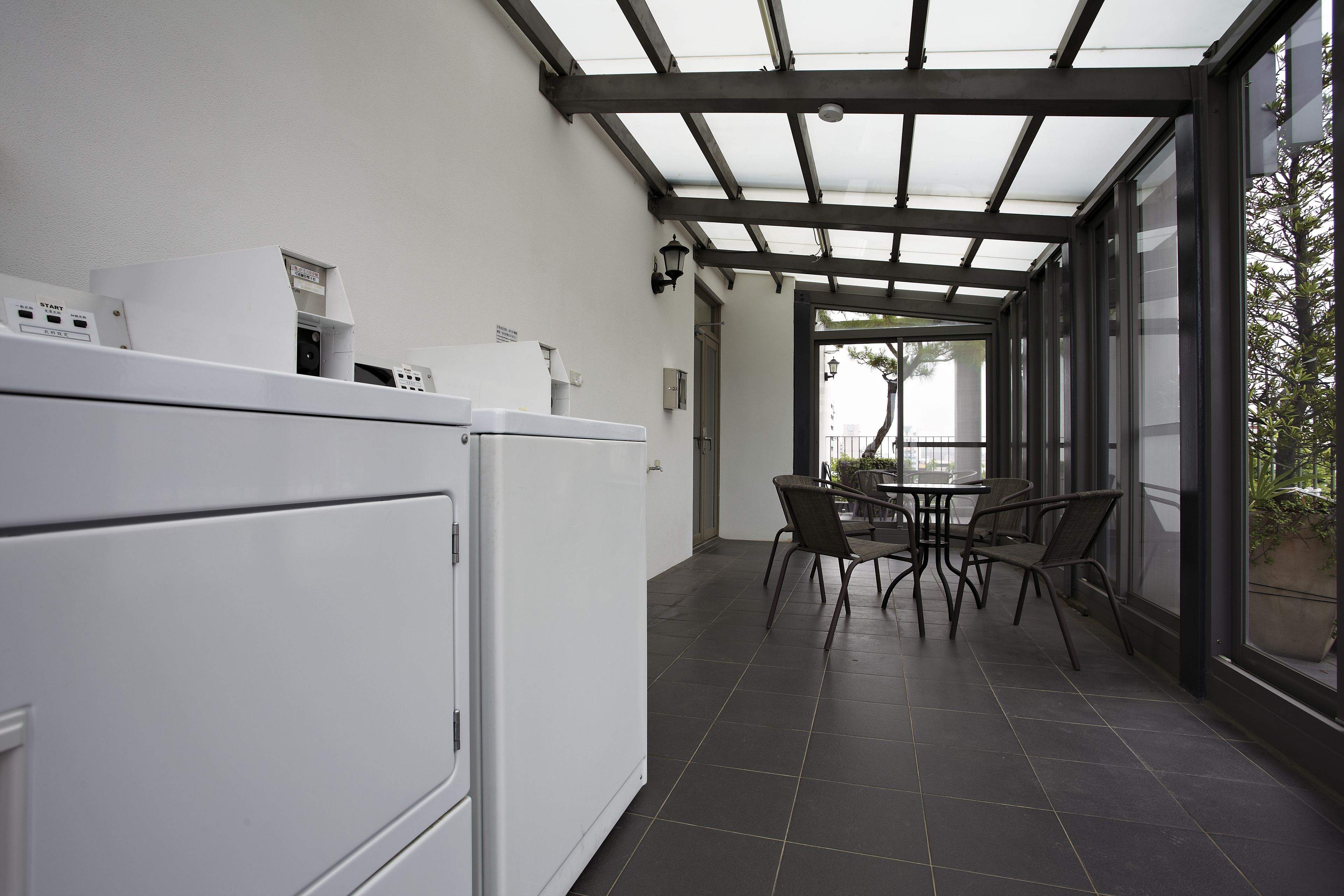 A modern kitchen with built-in appliances and a dining area with a glass wall overlooking a garden.