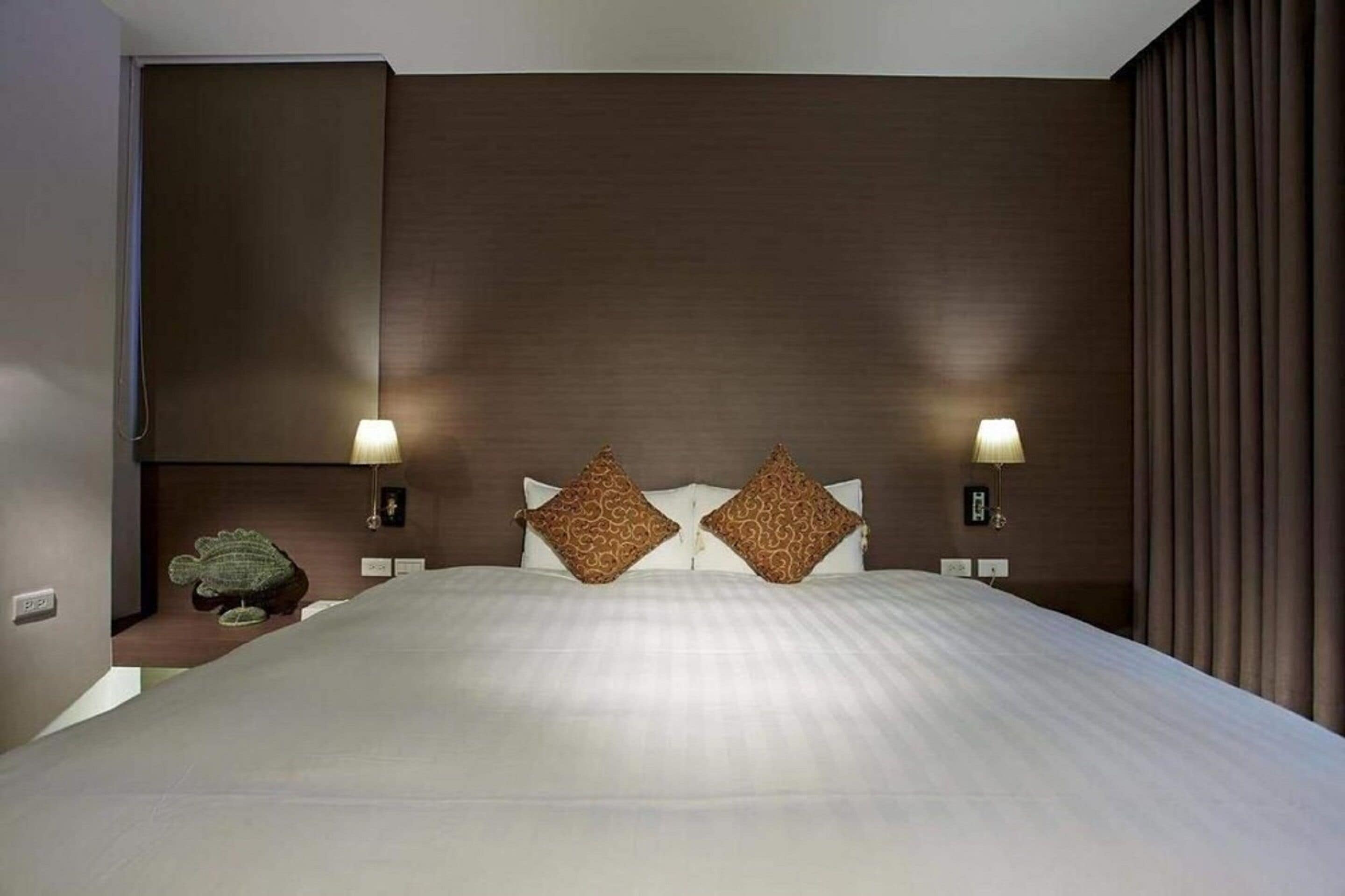 A hotel room with a large bed, two nightstands, two lamps, and a decorative frog statue.