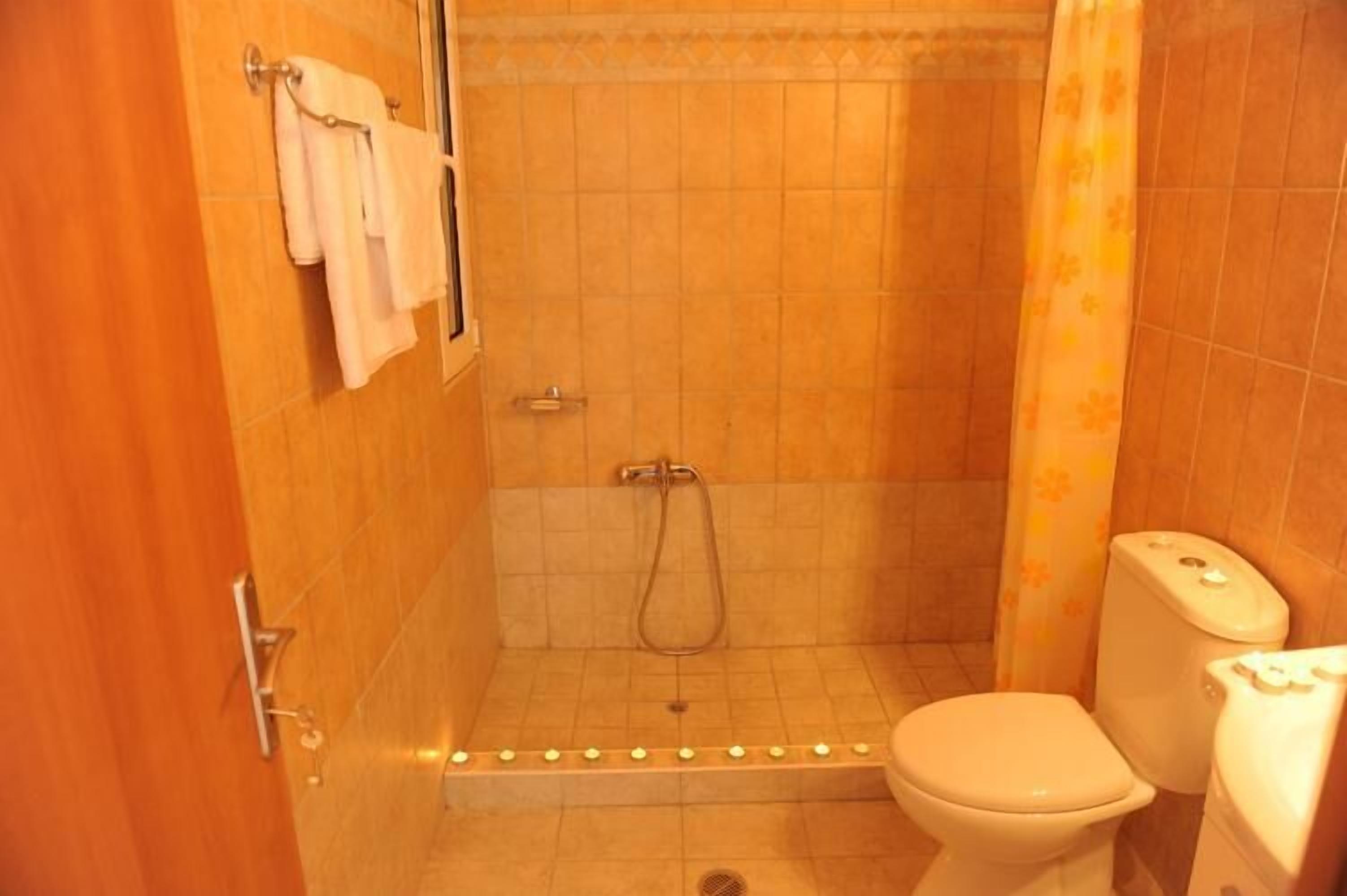 Un baño pequeño con azulejos, ducha, inodoro y toallero.
