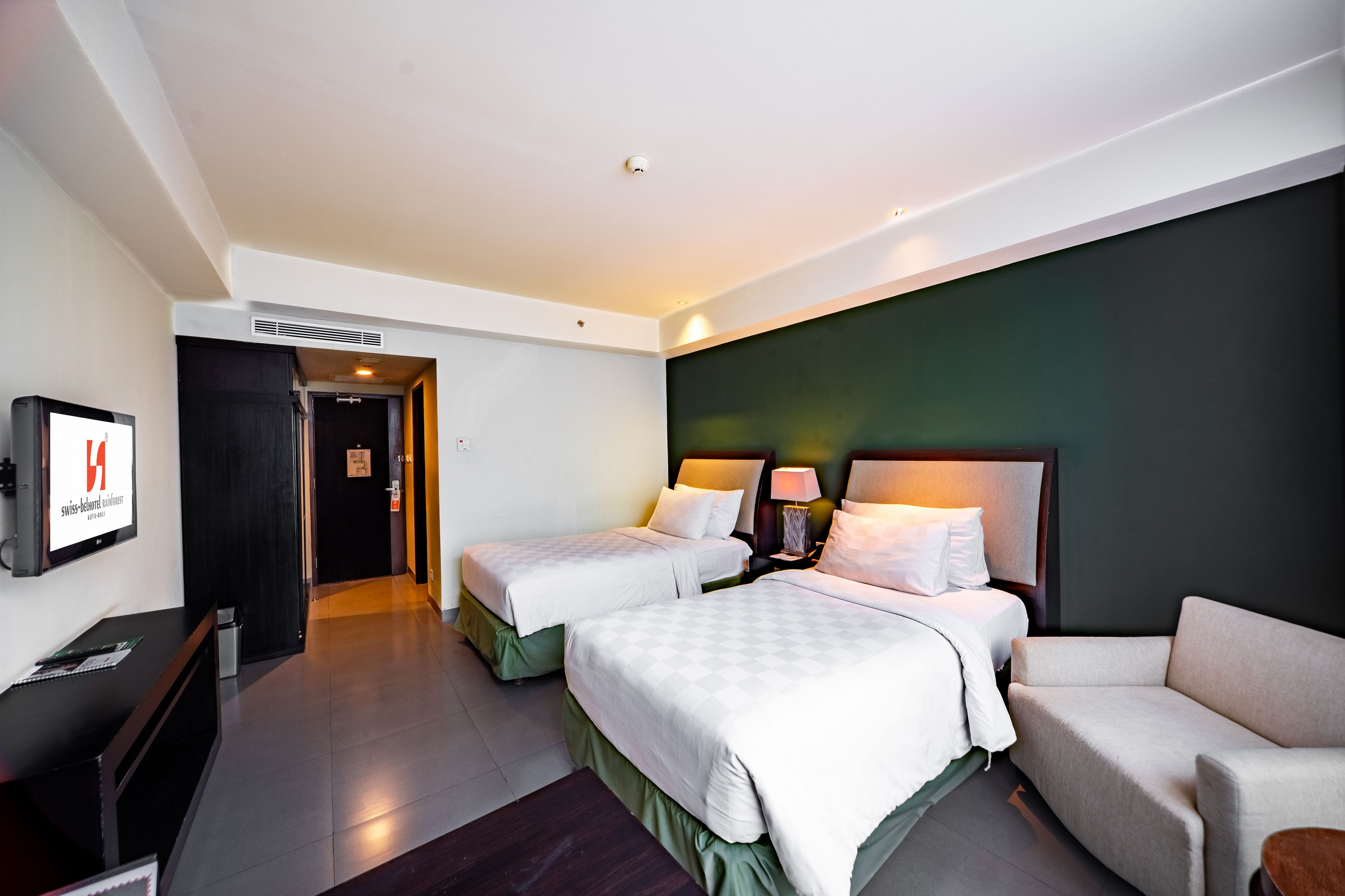 Une chambre d’hôtel avec deux lits, un canapé, une télévision et un bureau.