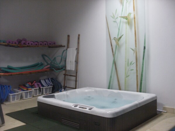 A bathroom with a hot tub, shelves with baskets, and a bamboo-themed shower curtain.