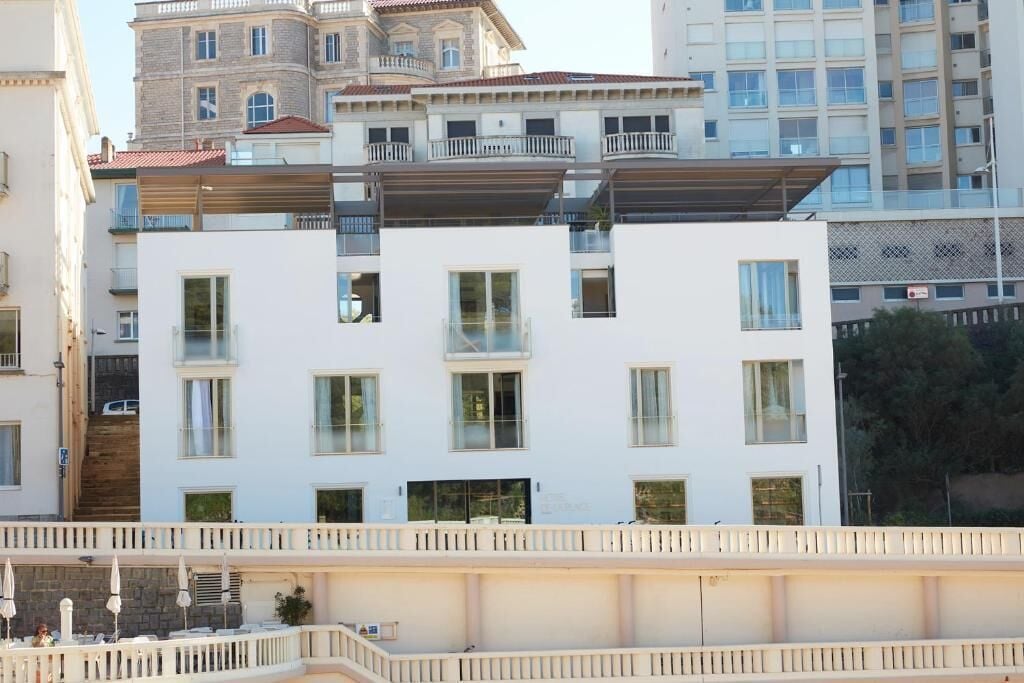 A multi-story building with balconies and large windows.