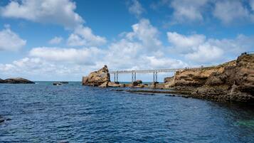 A coastal view with a bridge over water, rocky cliffs, and clear skies.