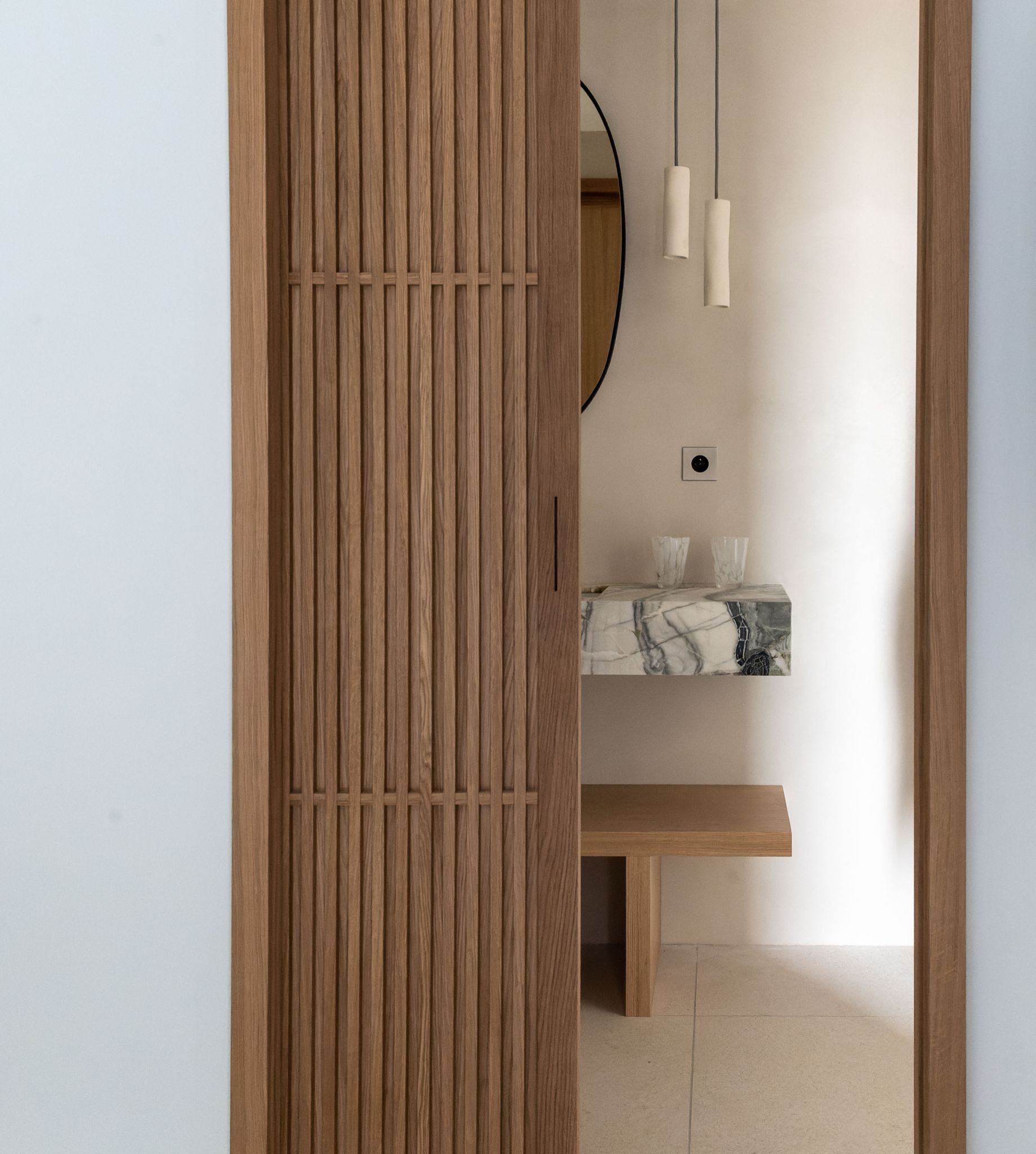 A wooden wardrobe with a mirror, a marble countertop, and pendant lights.