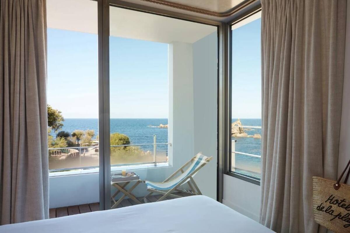 Ein Hotelzimmer mit einem großen Balkon, einem Bett und Meerblick.