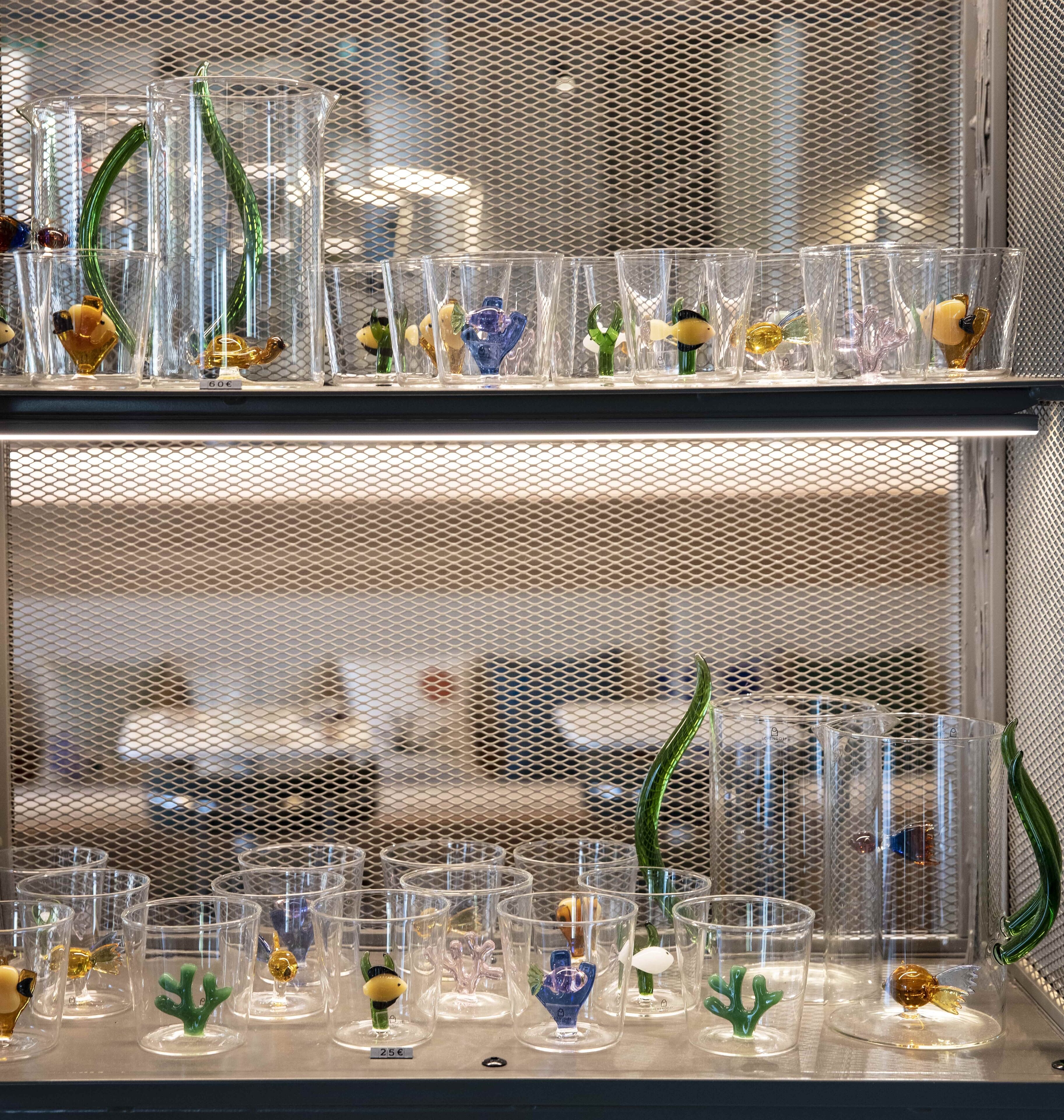 A display of clear glass containers with various decorative items inside, arranged on shelves.