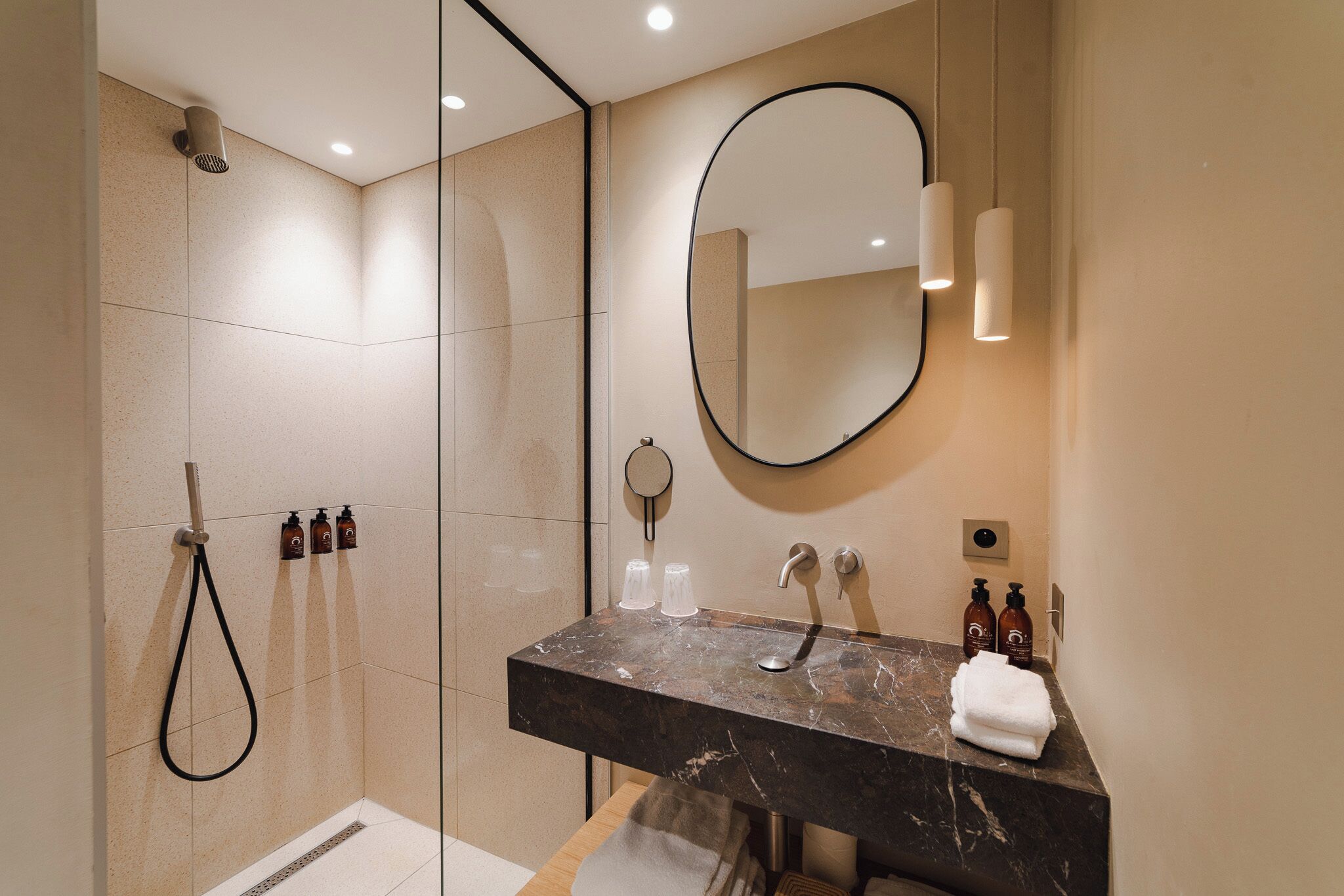 A modern bathroom with a glass-enclosed shower, a marble sink, and a large mirror.