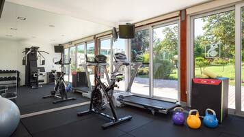 Une salle de sport équipée de machines de cardio, de poids libres et de kettlebells.