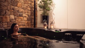 A spa setting with a stone wall, a potted plant, and a hot tub. - Hotel de Charme Casa da Amieira (Santarém)