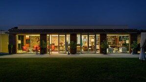 A modern house with a glass facade, outdoor seating, and a visible clock. - Hotel de Charme Casa da Amieira (Santarém)
