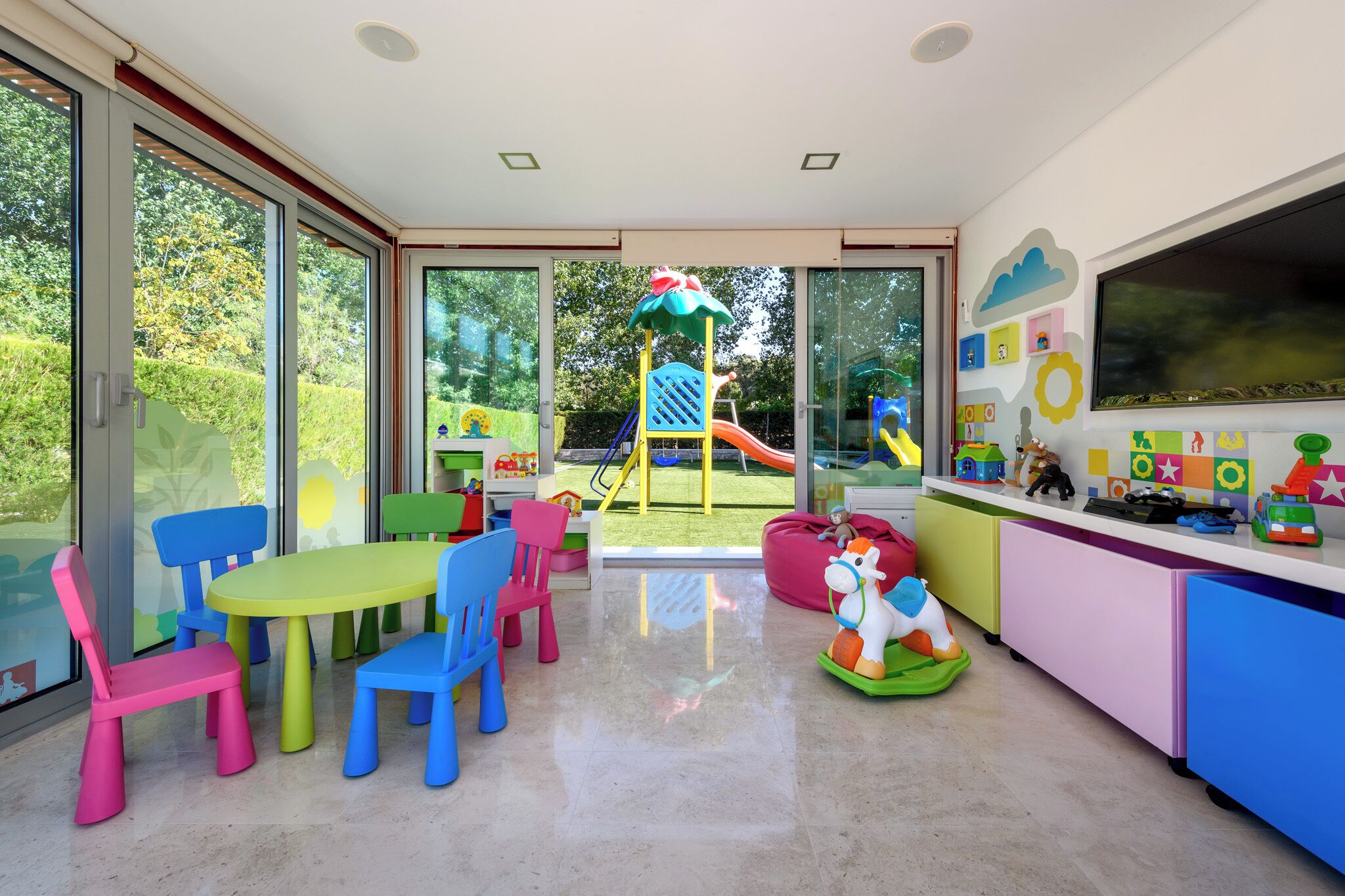 Une salle de jeux pour enfants avec un toboggan, des chaises colorées et des jouets.