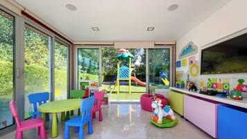 Une salle de jeux pour enfants avec un toboggan, des chaises colorées et des jouets.