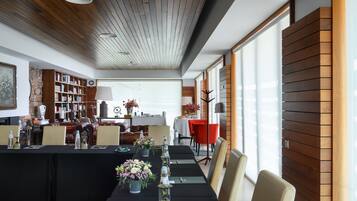 A modern dining area with a long table set for a meal, surrounded by wooden paneling and large windows.