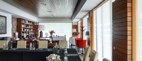 A modern dining area with a long table set for a meal, surrounded by wooden paneling and large windows.