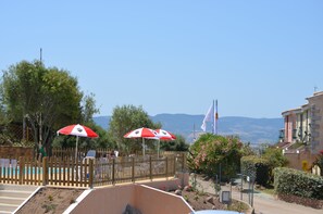 Una piscina al aire libre, sombrillas, sillones reclinables de piscina