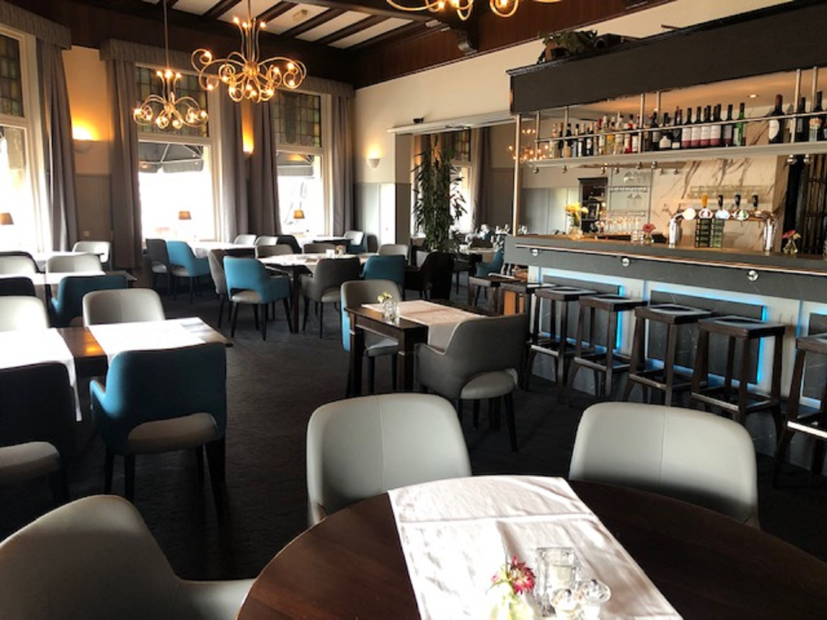 A restaurant with a bar area, tables, and chairs.