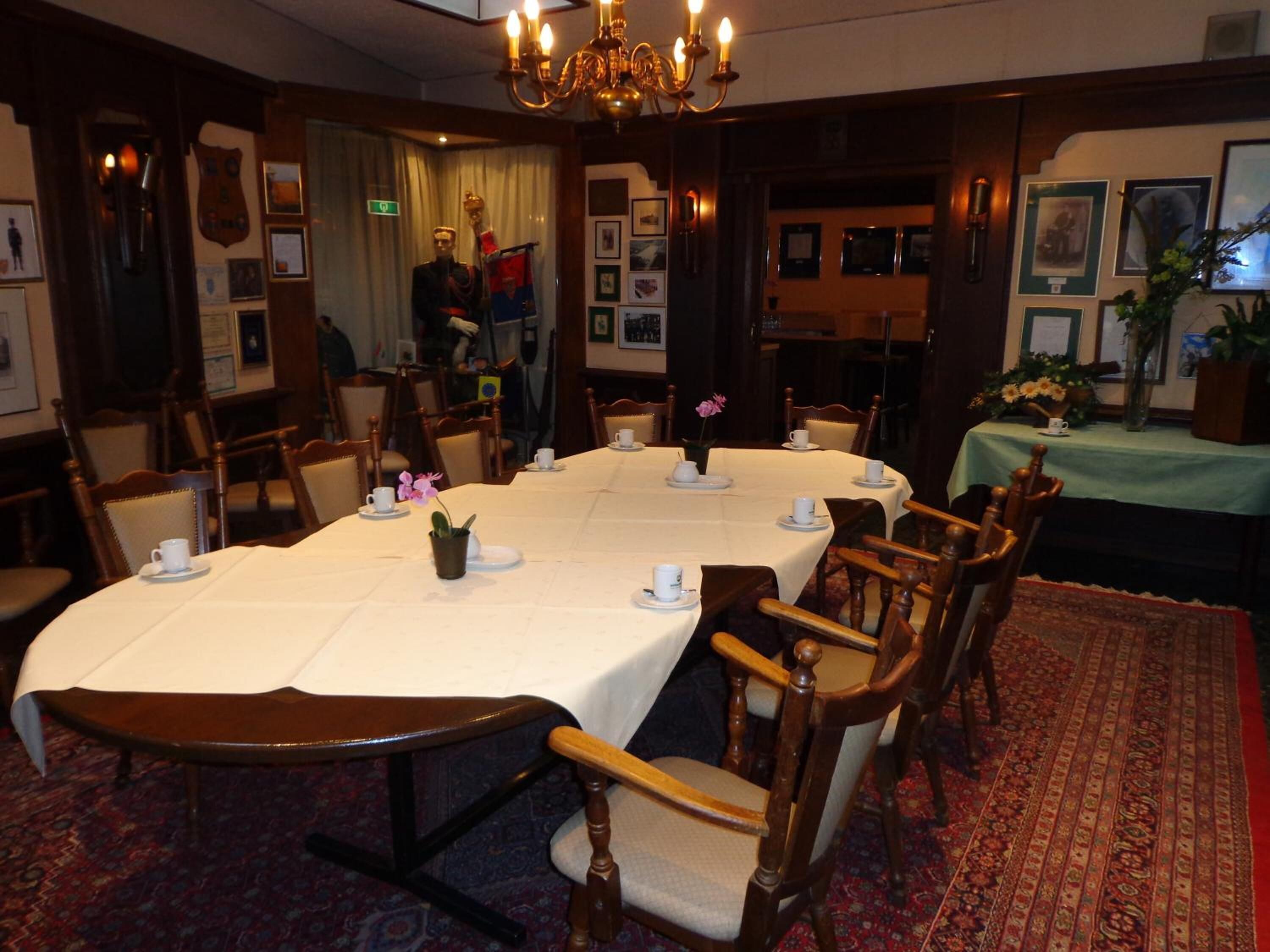 A formal dining room with a long table set for a meal, surrounded by wooden chairs.