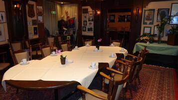 A formal dining room with a long table set for a meal, surrounded by wooden chairs.
