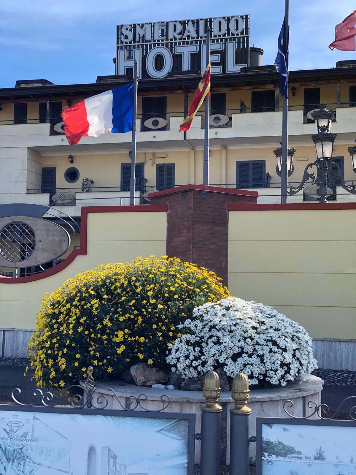 A hotel with a sign reading "SMERADDO HOTEL" and multiple flags, including the French flag.