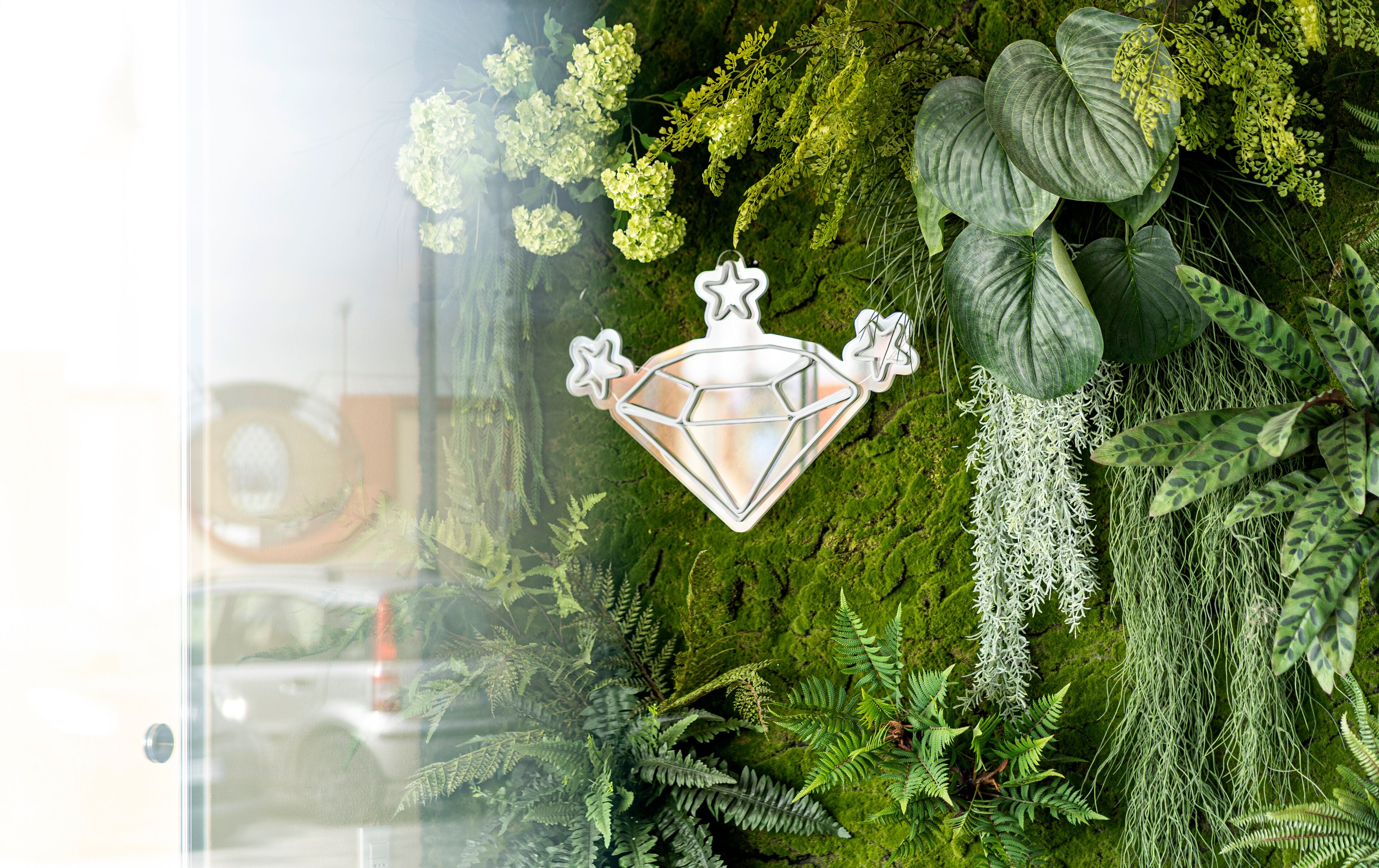 Un muro con un'apertura decorativa a forma di diamante e una rigogliosa vegetazione verde.