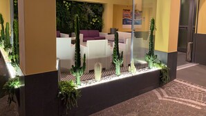 A lobby with a seating area, a glass partition, and a wall with greenery. - Hotel Smeraldo (Qualiano)