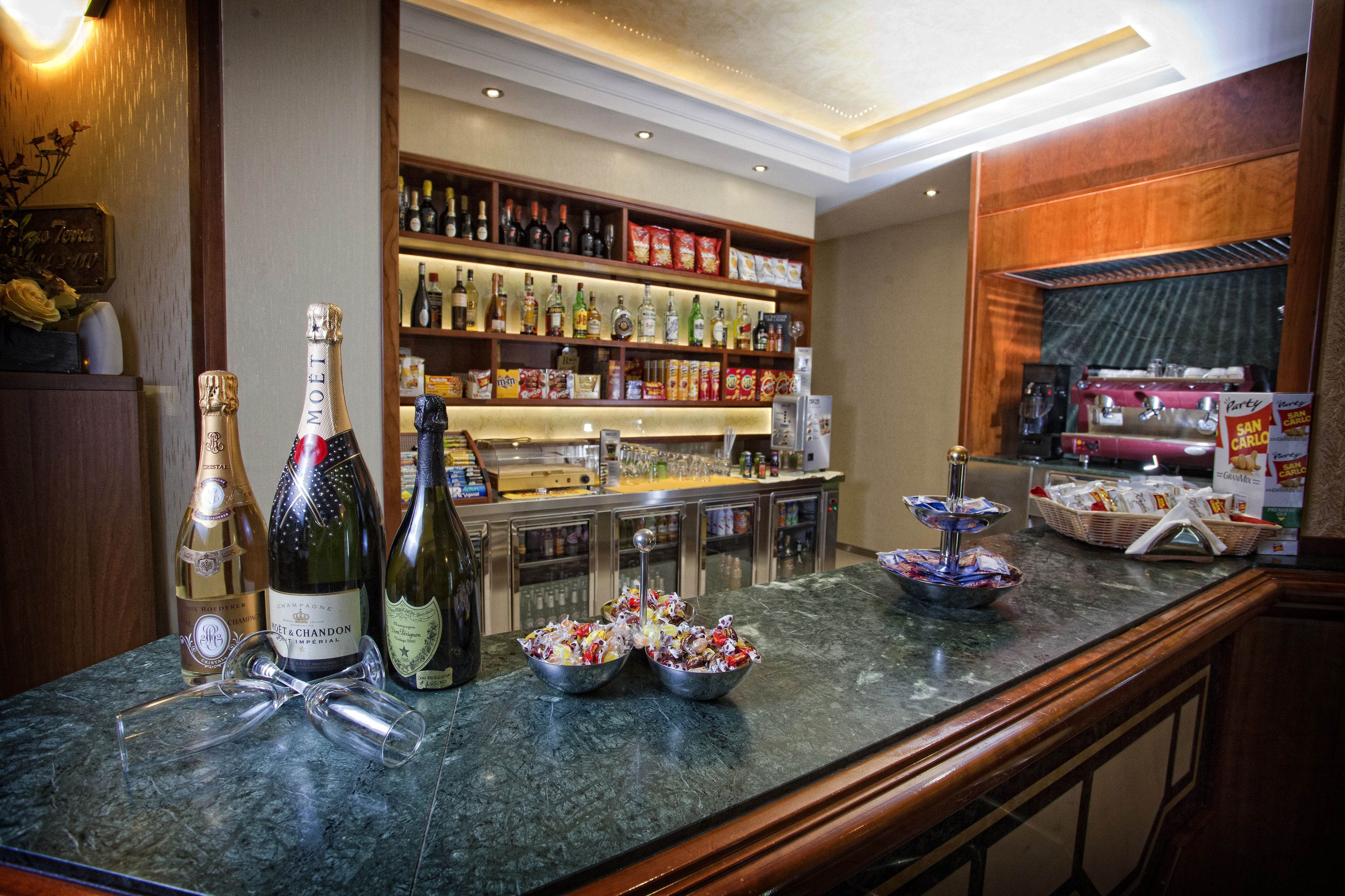 A bar area with bottles of wine, glasses, and snacks.