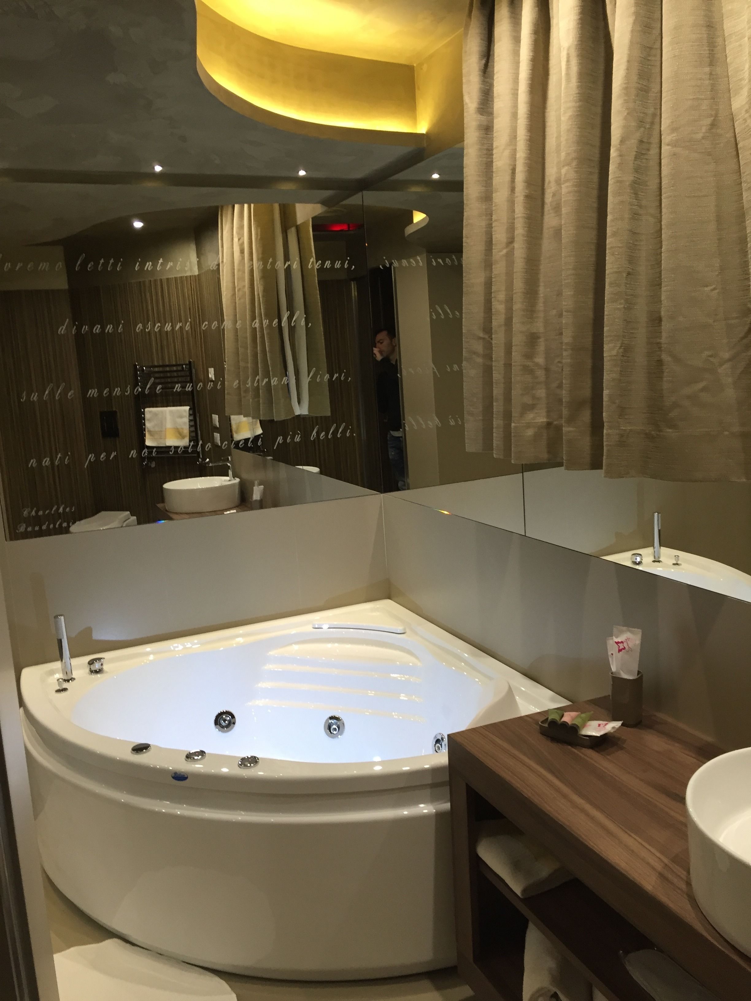 A modern bathroom with a large bathtub, a wooden vanity, and a mirror above the sink.