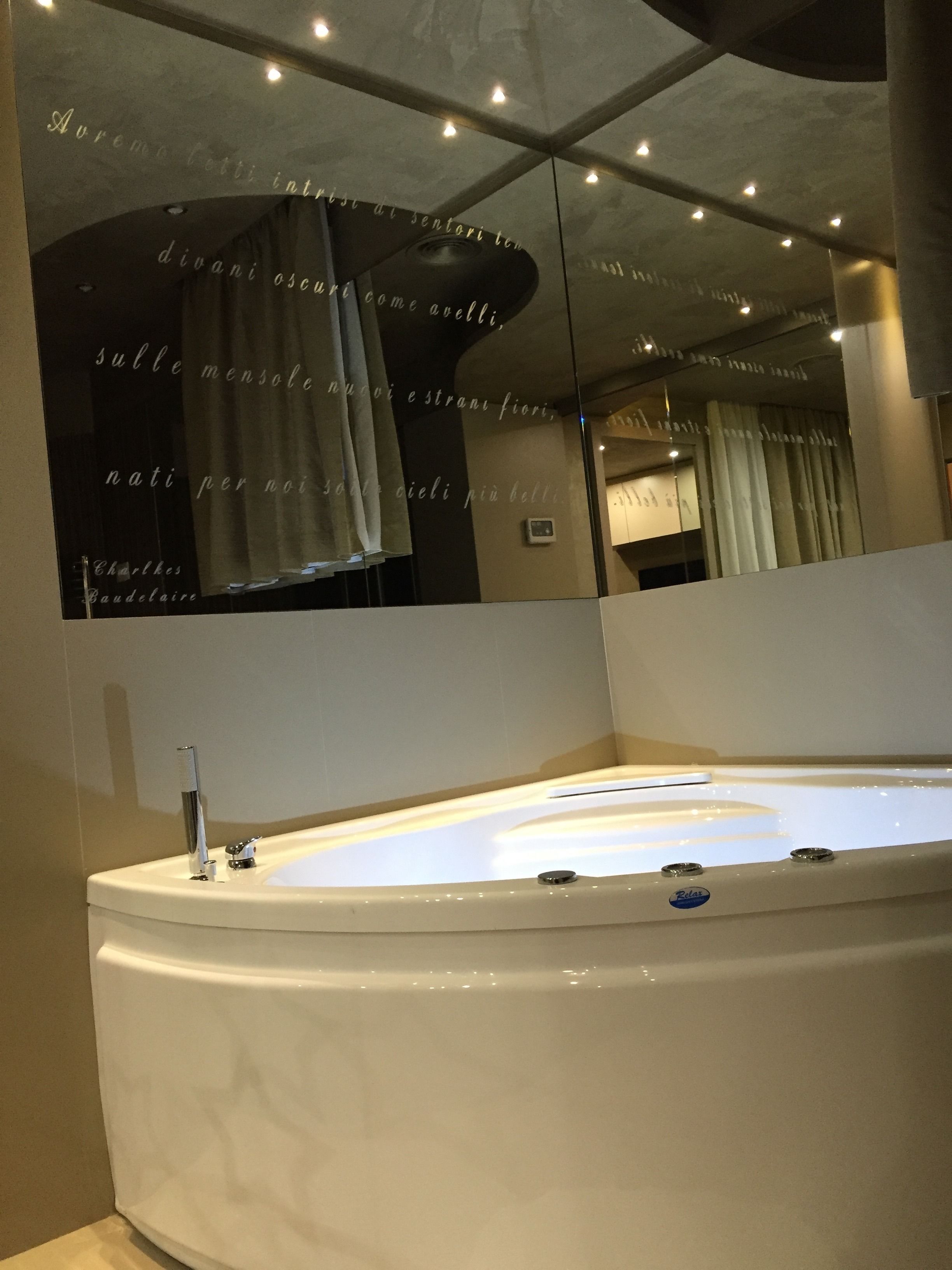 A modern bathroom with a large bathtub, a mirror, and a wall with text.