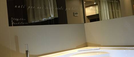 A modern bathroom with a large bathtub, a mirror, and a wall with text.