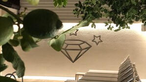 A room with a bed, a wall with a geometric design, and a plant in the foreground. - Hotel Smeraldo (Qualiano)