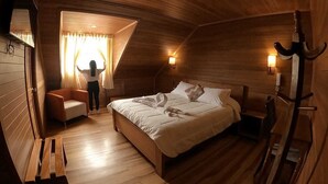 A cozy, wooden-paneled bedroom with a bed, a chair, and a desk. - Hotel Heidinger (Oxapampa)