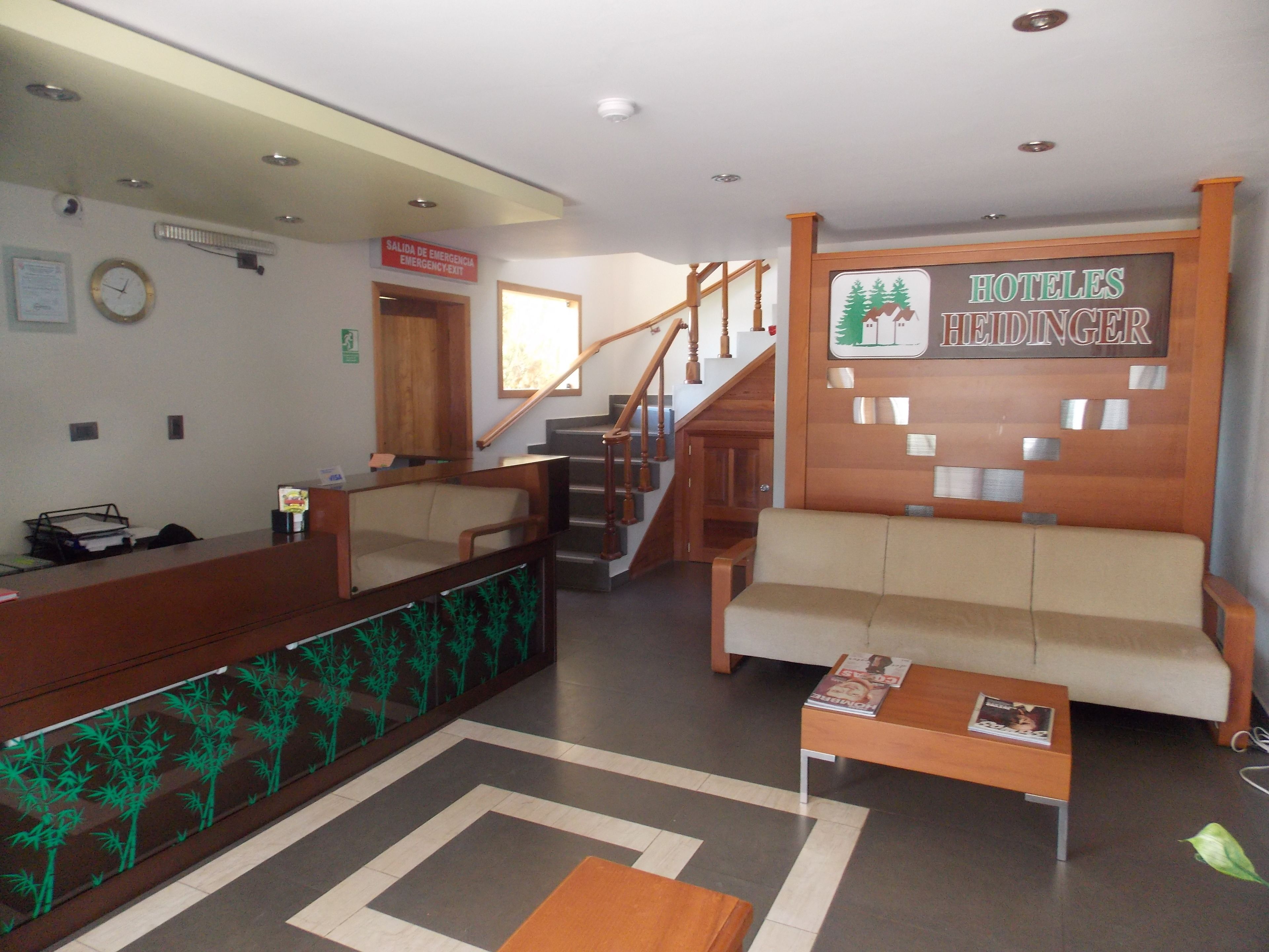 Un hall de hotel con una recepción, una escalera y un cartel que dice 'HOTEL HEIDINGER'.