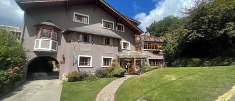 A large, multi-story building with a sloped roof, multiple windows, and a well-maintained lawn.