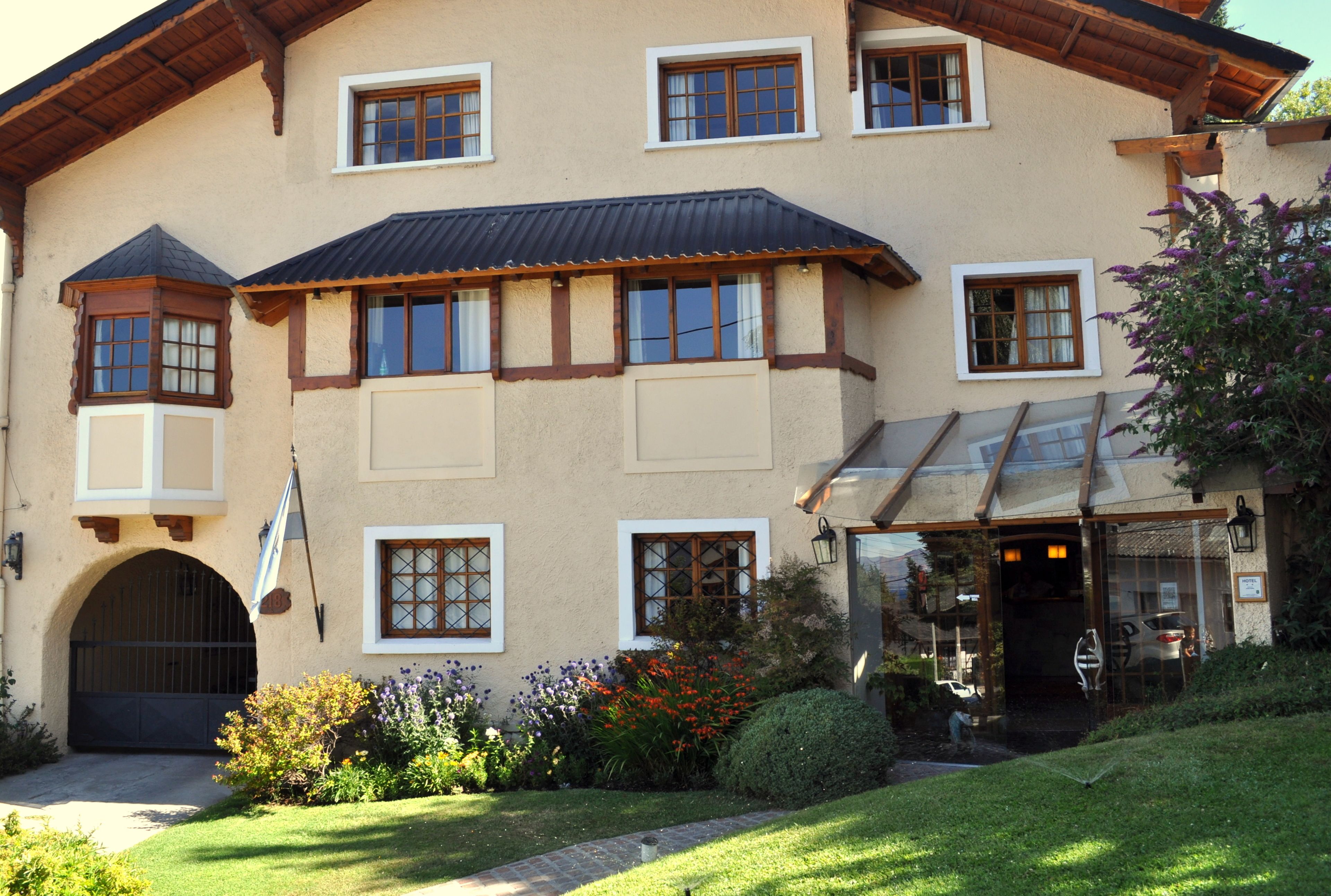 A large, two-story building with multiple windows, a covered entrance, and a well-maintained garden.