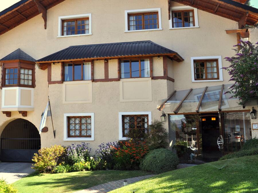 A large, two-story building with multiple windows, a covered entrance, and a well-maintained garden.