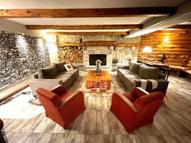 Una sala de estar acogedora con una chimenea de piedra, vigas de madera y un gran mural en la pared.