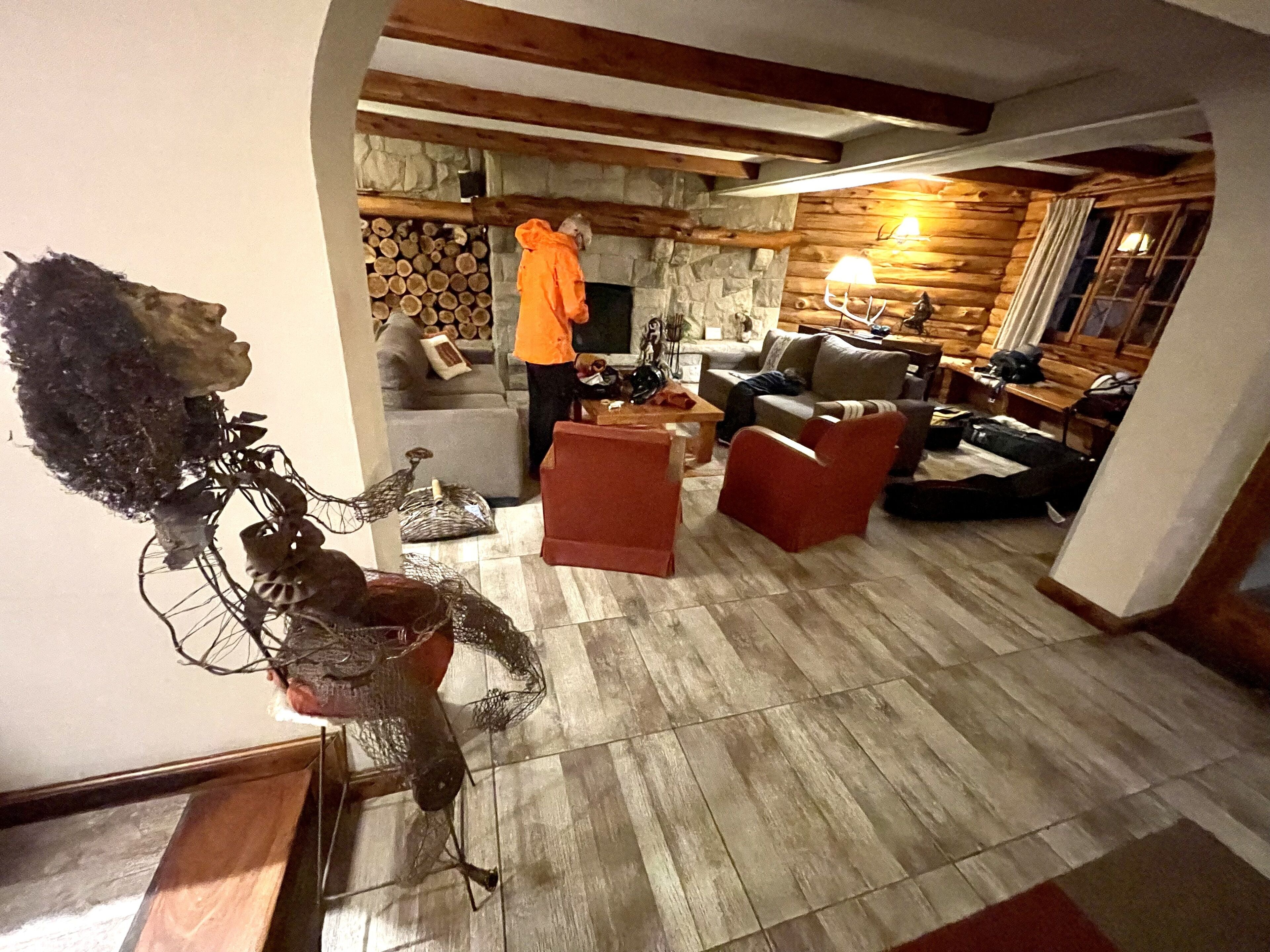 A cozy living room with a stone fireplace, wooden beams, and a statue.