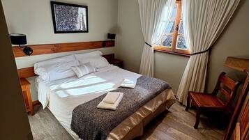 A neatly arranged bedroom with a bed, bedside table, lamp, and a window with curtains.