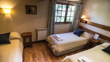 Ein Hotelzimmer mit zwei Betten, einem Fenster mit Vorhängen, einem Heizkörper und Wandleuchten.
