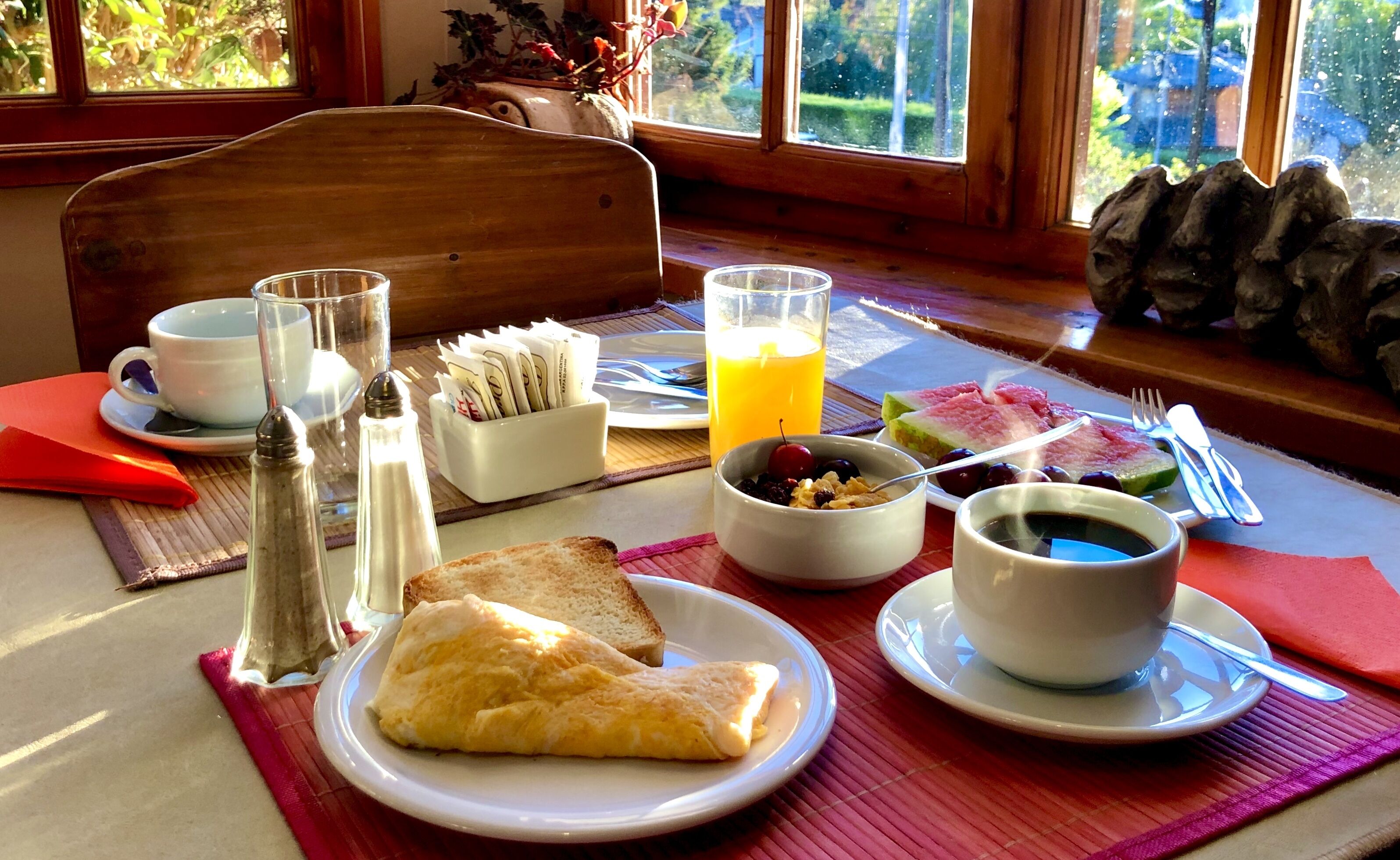 Una mesa de desayuno con diversos alimentos, como tostadas, fruta y una bebida caliente.