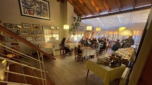 Un restaurante con suelos y mesas de madera, una escalera y cuadros en las paredes.